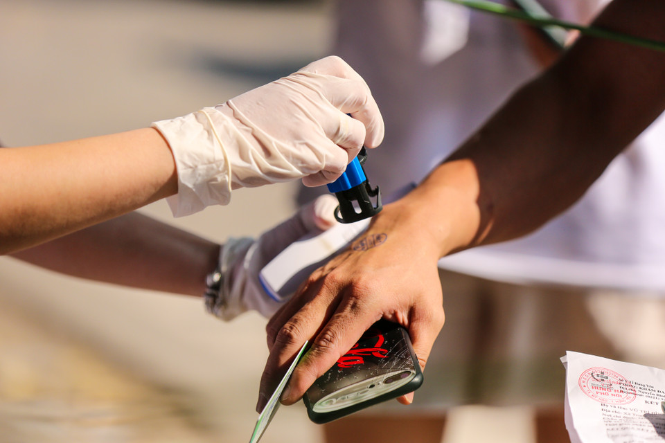 Khi đủ điều kiện, người dân cũng phải khai báo y tế với lực lượng chức năng và được đóng dấu trên tay để vào nội đô. (Ảnh: Minh Sơn/Vietnam+)