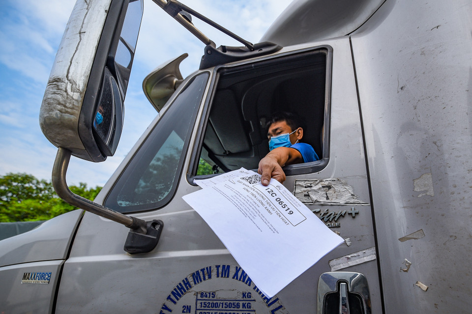 Hiện nay, do lượng yêu cầu cấp thẻ xe 'luồng xanh' lớn nên nhiều xe chở nông sản chưa thể có được tấm thẻ này để lưu thông qua Hà Nội. Nắm bắt được tình trạng này, tại một số chốt kiểm soát, lực lượng chức năng vẫn tạo điều kiện cho xe chở nông sản đi qua, với điều kiện đáp ứng được yêu cầu về y tế. (Ảnh: Minh Sơn/Vietnam+)