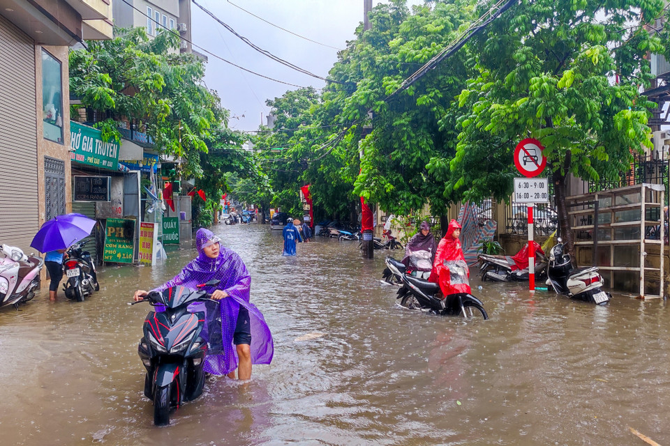 Người dân phải dong xe qua những chỗ ngập sâu vì chết máy. (Ảnh: Hoài Nam/Vietnam+)