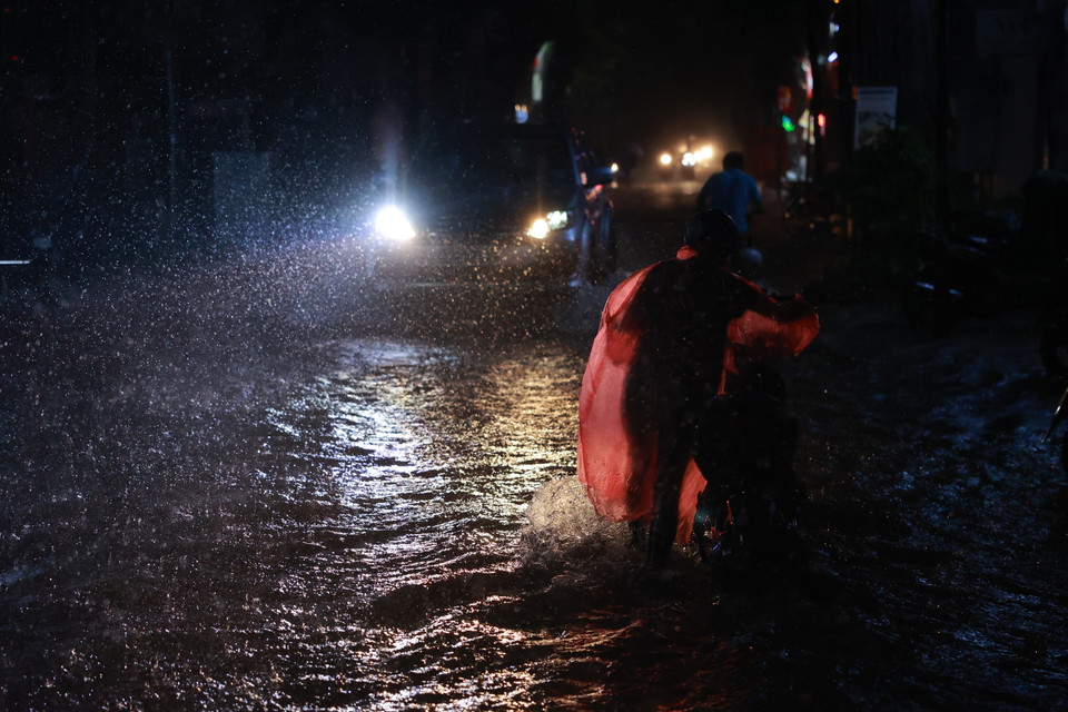 Các phương tiện di chuyển qua các tuyến phố ngập sâu rất khó khăn. (Ảnh: Minh Sơn/Vietnam+)