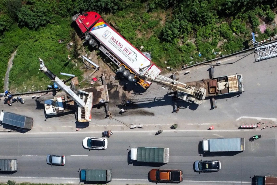 Chiếc xe container bị lật trên đường lên cầu Thanh Trì đã húc đổ cột biển báo, kéo đổ nghiêng cột khung biển báo hiệu, gây ùn tắc giao thông. (Ảnh: Huy Hùng/TTXVN)