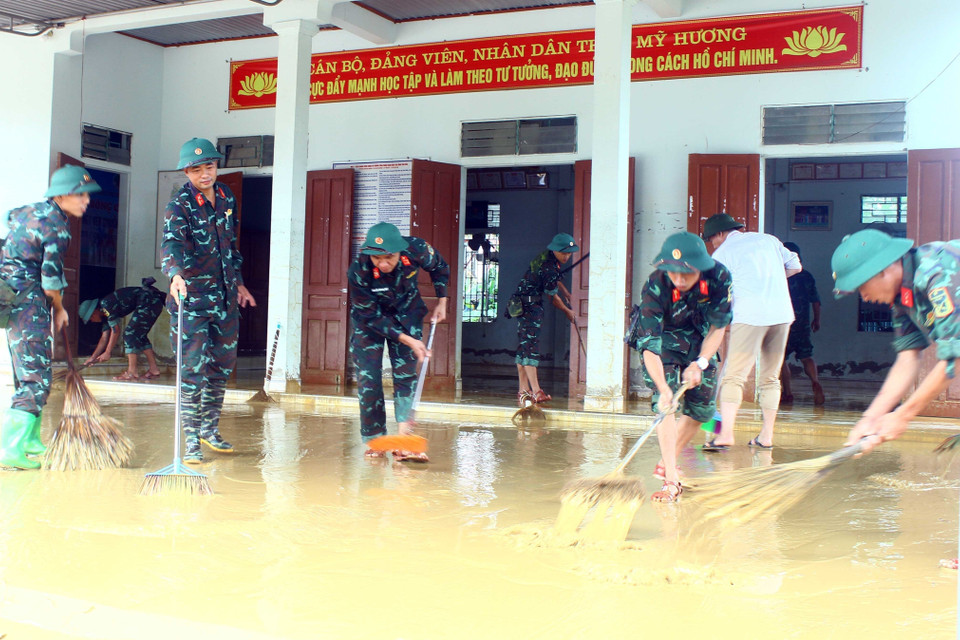 Cán bộ chiến sỹ Sư đoàn 324 đẩy bùn đất, vệ sinh tại nhà văn hóa thôn Mỹ Hương (xã Thanh Mỹ, huyện Thanh Chương). (Ảnh: Tá Chuyên/TTXVN)