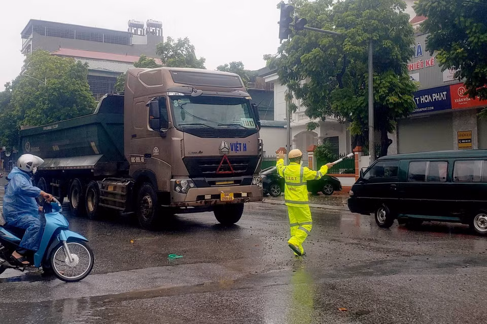 Cảnh sát giao thông phân luồng cho các phương tiện tham gia giao thông tránh đi vào các vùng bị ngập nước tại thành phố Vĩnh Yên. (Ảnh: Hoàng Hùng/TTXVN)