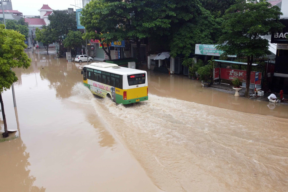 Chỉ có những xe gầm cao mới có thể vượt qua những đoạn đường ngập sâu trong nước trên đường Tôn Đức Thắng, thành phố Vĩnh Yên. (Ảnh: Hoàng Hùng/TTXVN)