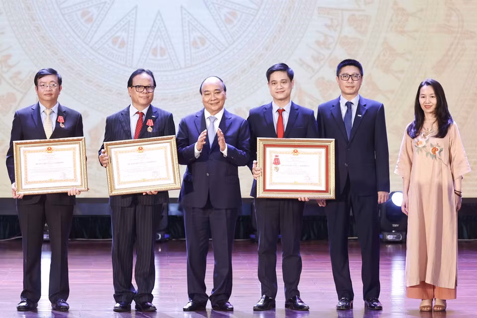 Chủ tịch nước Nguyễn Xuân Phúc trao tặng Huân chương Lao động hạng Ba cho tập thể và các nhân Trường Đại học Kinh tế Quốc dân. (Ảnh: Thống Nhất/TTXVN)