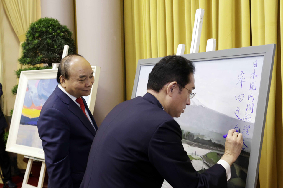 Thủ tướng Nhật Bản Kishida Fumio ký tặng Chủ tịch nước Nguyễn Xuân Phúc tác phẩm hội họa của họa sỹ Việt Nam về phong cảnh Nhật Bản. (Ảnh: Thống Nhất/TTXVN)