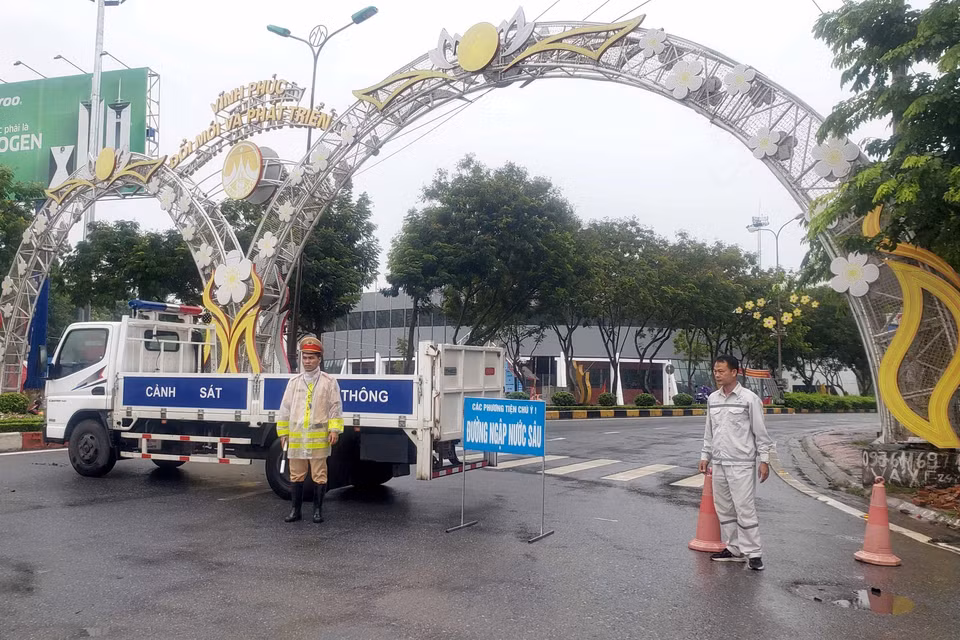 Cảnh sát giao thông phân luồng cho các phương tiện tham gia giao thông tránh đi vào các vùng bị ngập nước tại thành phố Vĩnh Yên. (Ảnh: Hoàng Hùng/TTXVN)