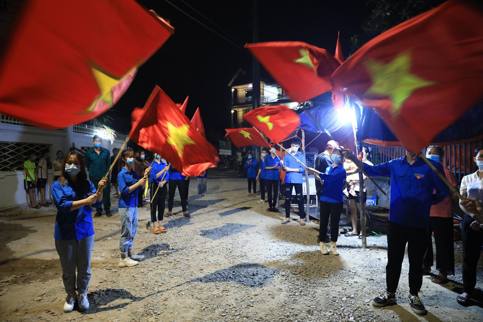 Lực lượng Đoàn Thanh niên thôn Lỗ Giao vui mừng phất cờ Tổ quốc sau khi có quyết định chính thức dỡ bỏ cách ly thôn. (Ảnh: Thành Đạt/TTXVN)