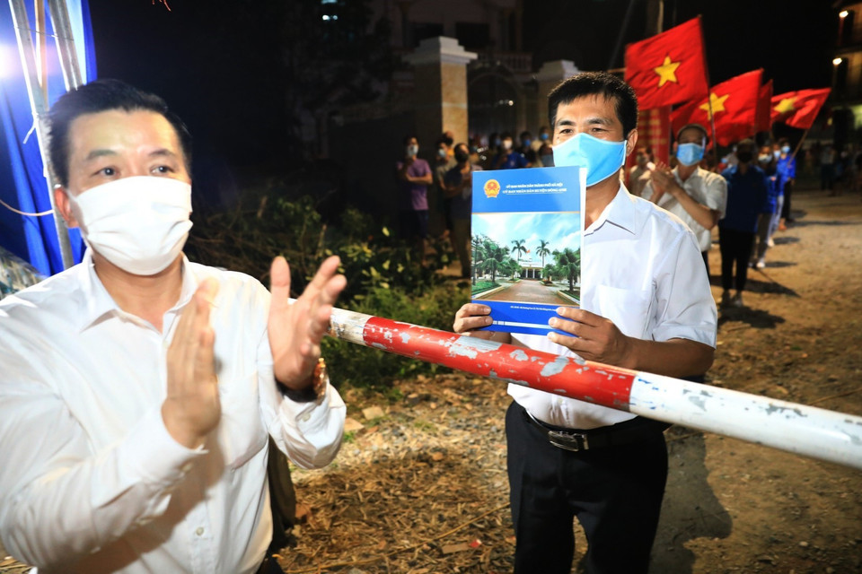 Lãnh đạo huyện Đông Anh trao quyết định dỡ bỏ cách ly cho ông Nguyễn Hữu Phan, Bí thư Chi bộ, Trưởng thôn Lỗ Giao. (Ảnh: Thành Đạt/TTXVN)