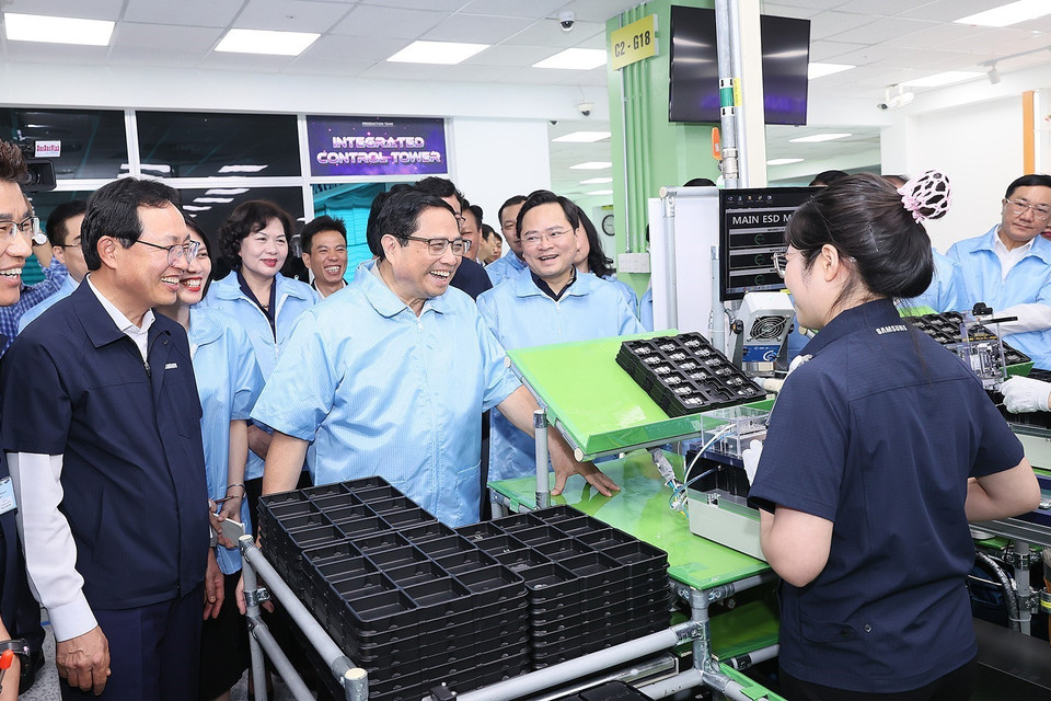 Thủ tướng Phạm Minh Chính thăm hỏi công nhân dây chuyền sản xuất thiết bị điện tử của Công ty TNHH Samsung Việt Nam. (Ảnh: Dương Giang/TTXVN)
