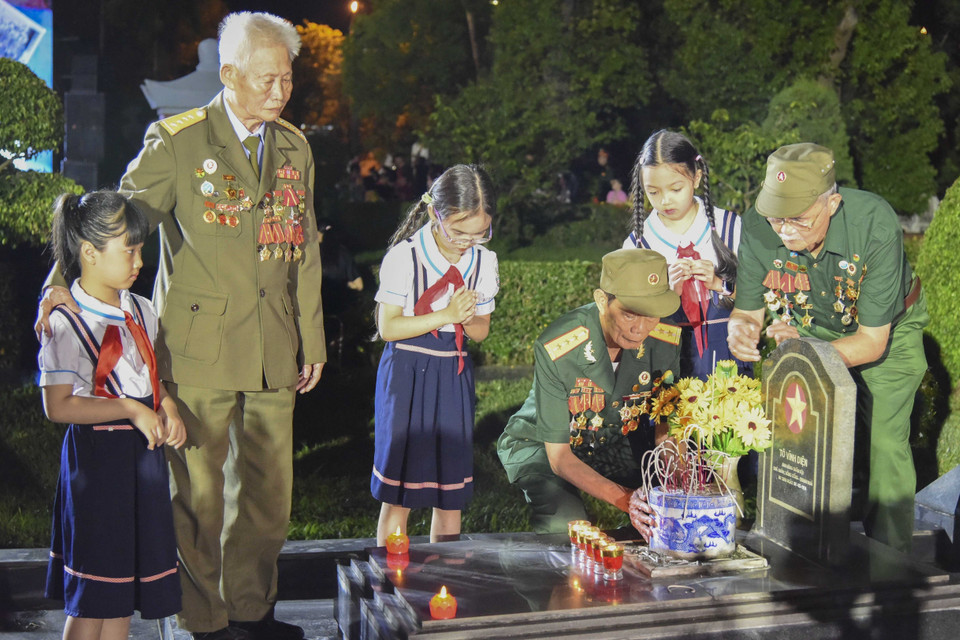 Các cựu chiến binh Điện Biên và các cháu thiếu nhi thắp hương lên các phần mộ liệt sỹ tại Nghĩa trang A1-Điện Biên. (Ảnh: Xuân Tư/TTXVN)