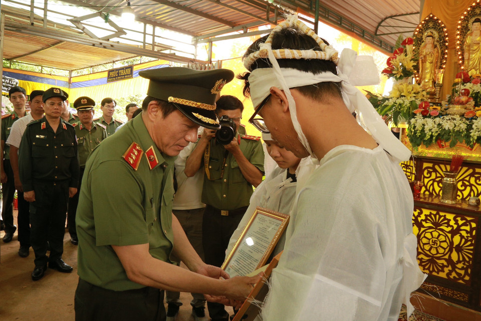 Thứ trưởng Bộ Công an Lương Tam Quang trao quyết định truy thăng cấp bậc hàm từ Đại úy lên Thiếu tá đối với chiến sỹ Hoàng Trung, hy sinh trong vụ tấn công bằng súng tại trụ sở xã Ea Tiêu và xã Ea Ktur, huyện Cư Kuin cho thân nhân gia đình. (Ảnh: Quang Thái/TTXVN)