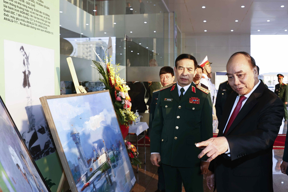 Chủ tịch nước Nguyễn Xuân Phúc và các đại biểu xem các bức tranh trưng bày tại buổi gặp mặt. (Ảnh: Thống Nhất/TTXVN)