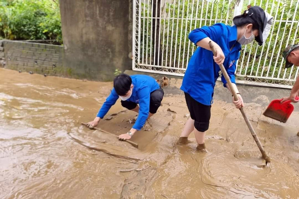 Các lực lượng khẩn trương dọn vệ sinh trên các tuyến đường sau khi nước rút. (Ảnh: TTXVN phát)