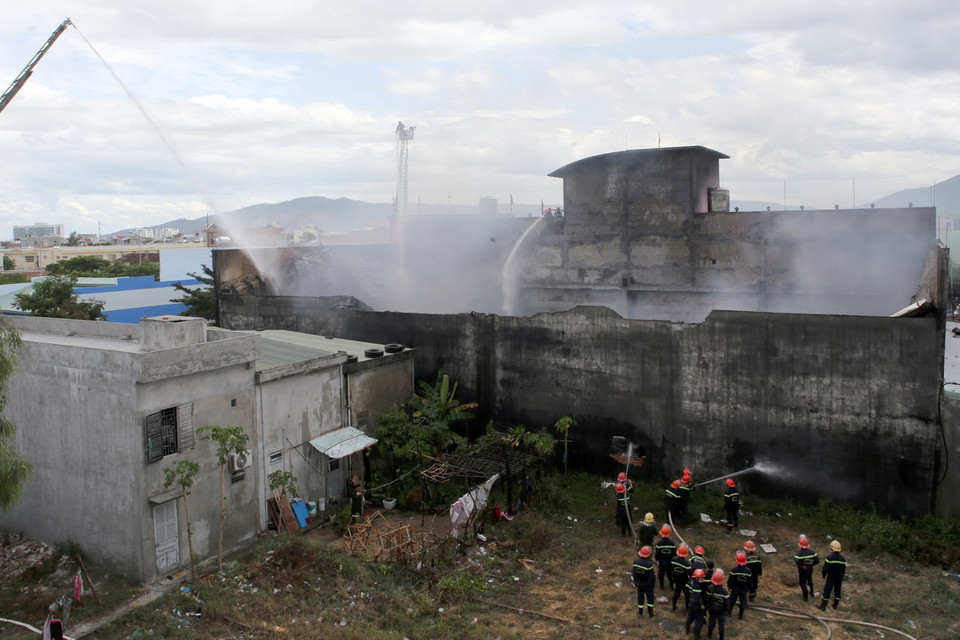 Các chiến sỹ cứu hỏa phải đập phá các mảng tường lớn để tiếp cận phun nước. (Ảnh: Lê Lâm/Vietnam+)