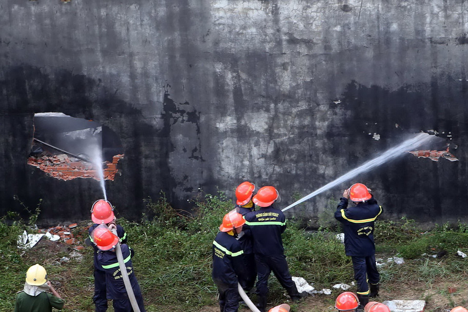 Các chiến sỹ cứu hỏa phải đập phá các mảng tường lớn để tiếp cận phun nước. (Ảnh: Lê Lâm/Vietnam+)