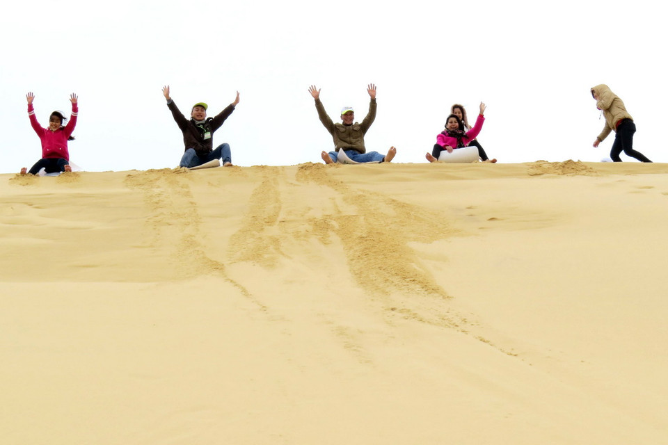 Du khách thích thú tham gia trò chơi trượt cát. (Ảnh: Mạnh Thành/TTXVN)
