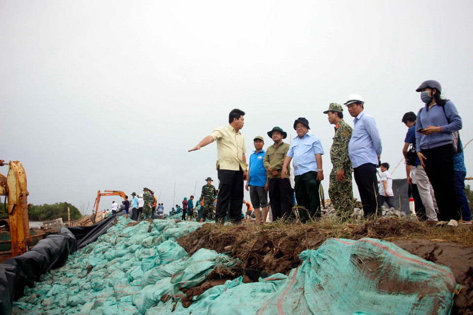 Chủ tịch Ủy ban Nhân dân tỉnh Cà Mau Nguyễn Tiến Hải (áo vàng) chỉ đạo lực lượng chức năng triển khai các giải pháp hộ đê. (Ảnh: Huỳnh Thế Anh/TTXVN)