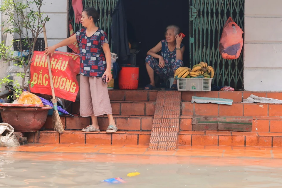 Người dân phố Cầu Đất (quận Hoàn Kiếm) dọn nhà cửa sau khi nước rút. (Ảnh: Hoàng Hiếu/TTXVN)