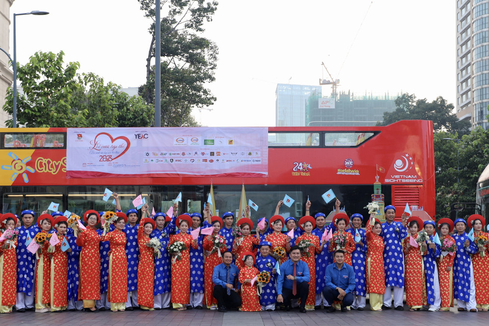 Các cặp vợ chồng thanh niên công nhân chuẩn bị tham gia phần diễu hành quanh Thành phố Hồ Chí Minh bằng xe buýt hai tầng. (Ảnh: Hồng Giang/TTXVN)