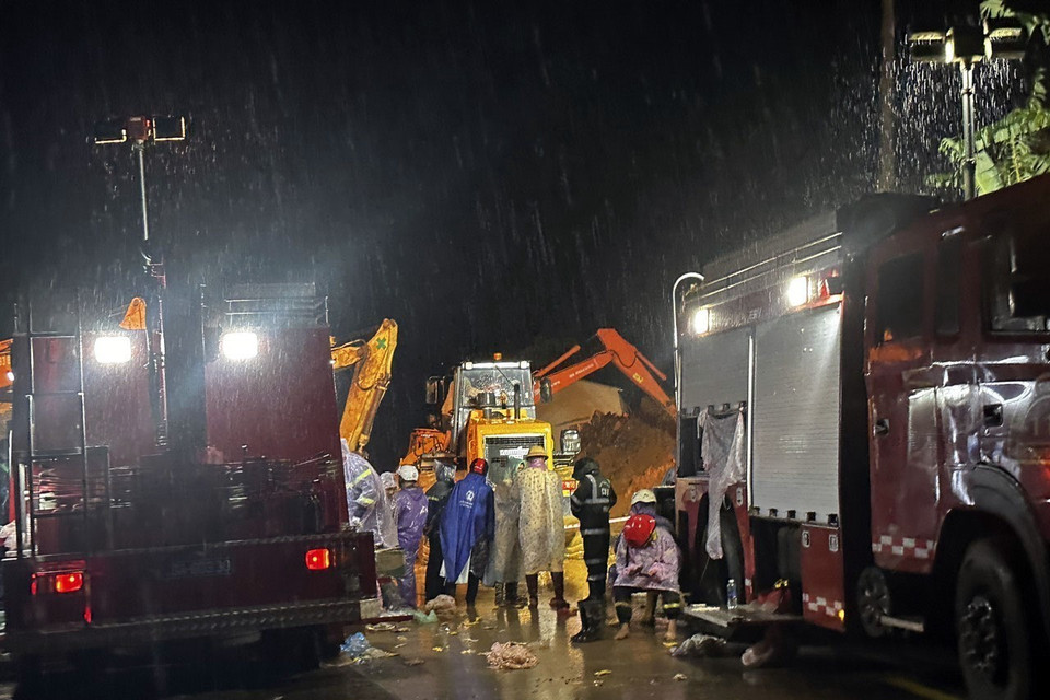 Mặc dù lực lượng chức năng khoảng 100 người, cùng nhiều phương tiện xe cơ giới, máy múc xuyên đêm thực hiện giải toả hiện trường nhưng do lượng đất đá quá lớn nên hiện mới chỉ dọn dẹp được một phần mặt đường để phục vụ công tác cứu hộ. (Ảnh: Nguyễn Dũng/TTXVN) 