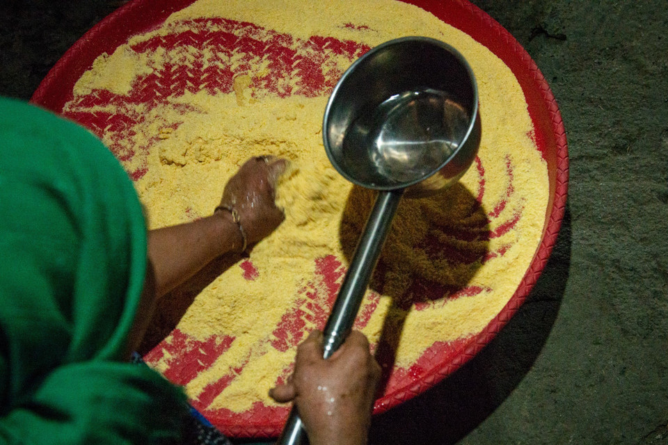 Ngô được xay nhiều lần cho đến khi trở thành bột mịn vừa ý, đổ bột vào nia, trộn cùng một chút nước. (Ảnh: Nam Thái/TTXVN)