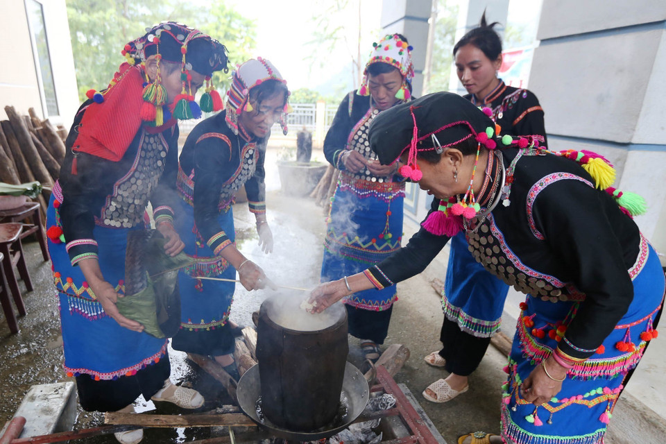 Các thành viên trong gia đình đồ xôi để giã bánh giầy. (Ảnh: Quý Trung/TTXVN)