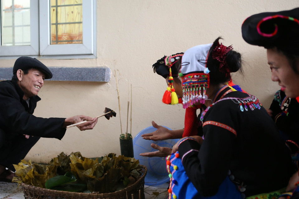 Sau khi cúng tổ tiên xong, thầy mo phát cho những thành viên mỗi người một miếng để ăn lấy may. (Ảnh: Quý Trung/TTXVN)