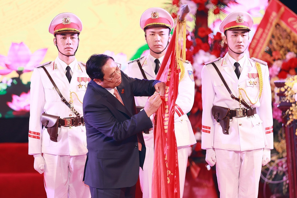 Thủ tướng Phạm Minh Chính gắn Huân chương Bảo vệ Tổ quốc hạng Nhất lên Cờ truyền thống của lực lượng An ninh Kinh tế. (Ảnh: Dương Giang/TTXVN)