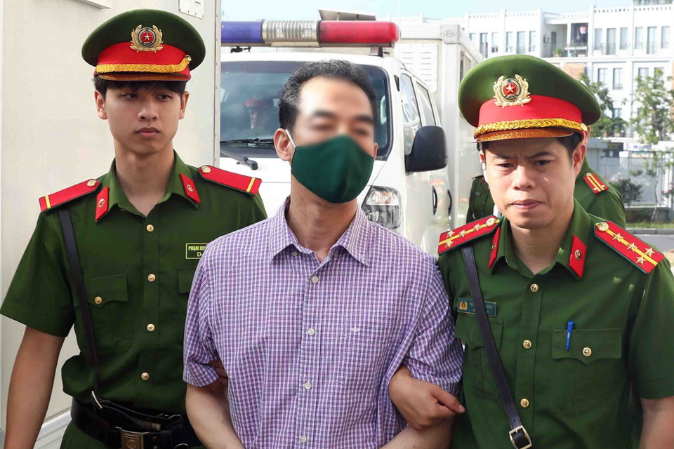 Lực lượng chức năng dẫn giải bị cáo Tô Anh Dũng, cựu Thứ trưởng Bộ Ngoại giao, tới phiên tòa xét xử. (Ảnh: Phạm Kiên/TTXVN)