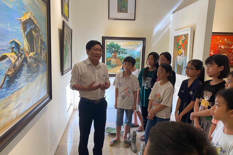 Họa sỹ Hoàng Tuấn Việt, Hội viên hội Mỹ thuật Việt Nam, Chủ nhiệm Câu lạc bộ Mỹ thuật Cổ Đô giới thiệu với các em về những bức tranh được trưng bày tại Bảo tàng Mỹ thuật Cổ Đô. (Nguồn: Vietnam+)