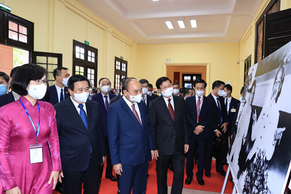 Phó Tổng Giám đốc Thông tấn xã Việt Nam Vũ Việt Trang giới thiệu trưng bày ảnh của TTXVN với Tổng Bí thư, Chủ tịch nước Lào Thongloun Sisoulith và Chủ tịch nước Nguyễn Xuân Phúc. (Ảnh: Thống Nhất/TTXVN)