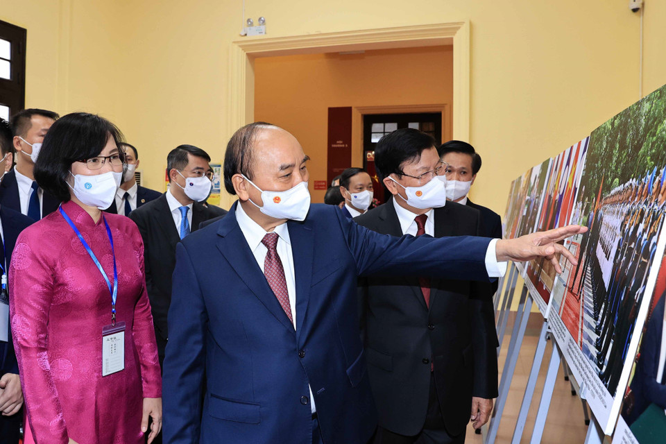 Phó Tổng Giám đốc Thông tấn xã Việt Nam Vũ Việt Trang giới thiệu trưng bày ảnh của TTXVN với Tổng Bí thư, Chủ tịch nước Lào Thongloun Sisoulith và Chủ tịch nước Nguyễn Xuân Phúc. (Ảnh: Thống Nhất/TTXVN)