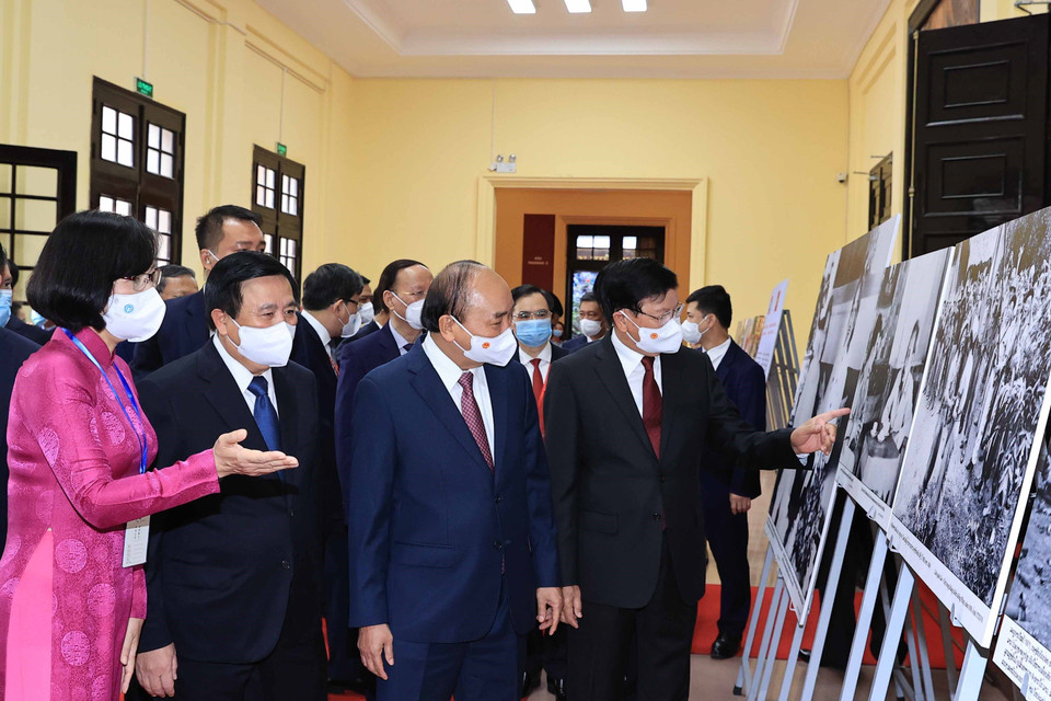 Phó Tổng Giám đốc Thông tấn xã Việt Nam Vũ Việt Trang giới thiệu trưng bày ảnh của TTXVN với Tổng Bí thư, Chủ tịch nước Lào Thongloun Sisoulith và Chủ tịch nước Nguyễn Xuân Phúc. (Ảnh: Thống Nhất/TTXVN)