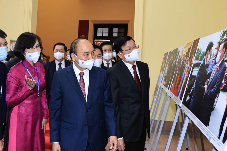 Phó Tổng Giám đốc Thông tấn xã Việt Nam Vũ Việt Trang giới thiệu trưng bày ảnh của TTXVN với Tổng Bí thư, Chủ tịch nước Lào Thongloun Sisoulith và Chủ tịch nước Nguyễn Xuân Phúc. (Ảnh: Thống Nhất/TTXVN)