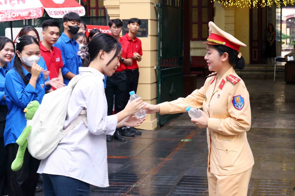 Cán bộ, chiến sỹ phòng Cảnh sát Giao thông, Công an thành phố Hà Nội phát nước, động viên các sỹ tử trước giờ thi. (Ảnh: Phạm Kiên/TTXVN)