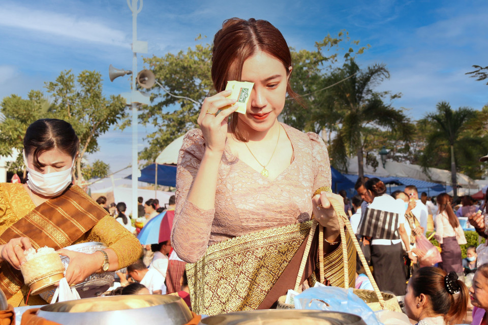 Một thiếu nữ Lào thực hiện nghi lễ Xaybath (Cúng dường), một trong những nghi lễ được thực hiện trong suốt hai ngày lễ Thatluang. (Ảnh: Phạm Kiên-Bá Thành/TTXVN)