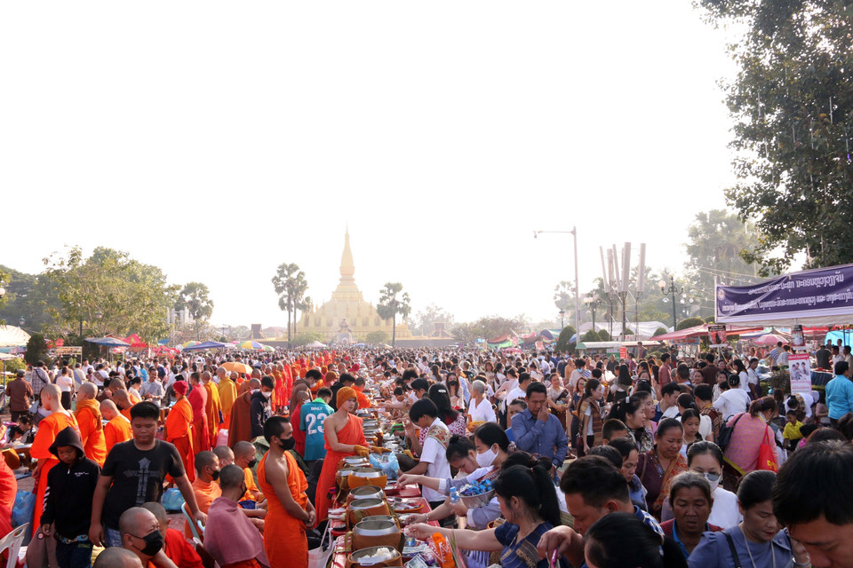 Người dân Lào thực hiện nghi lễ Xaybath (Cúng dường), một trong những nghi lễ được thực hiện trong suốt hai ngày lễ Thatluang. (Ảnh: Phạm Kiên-Bá Thành/TTXVN)