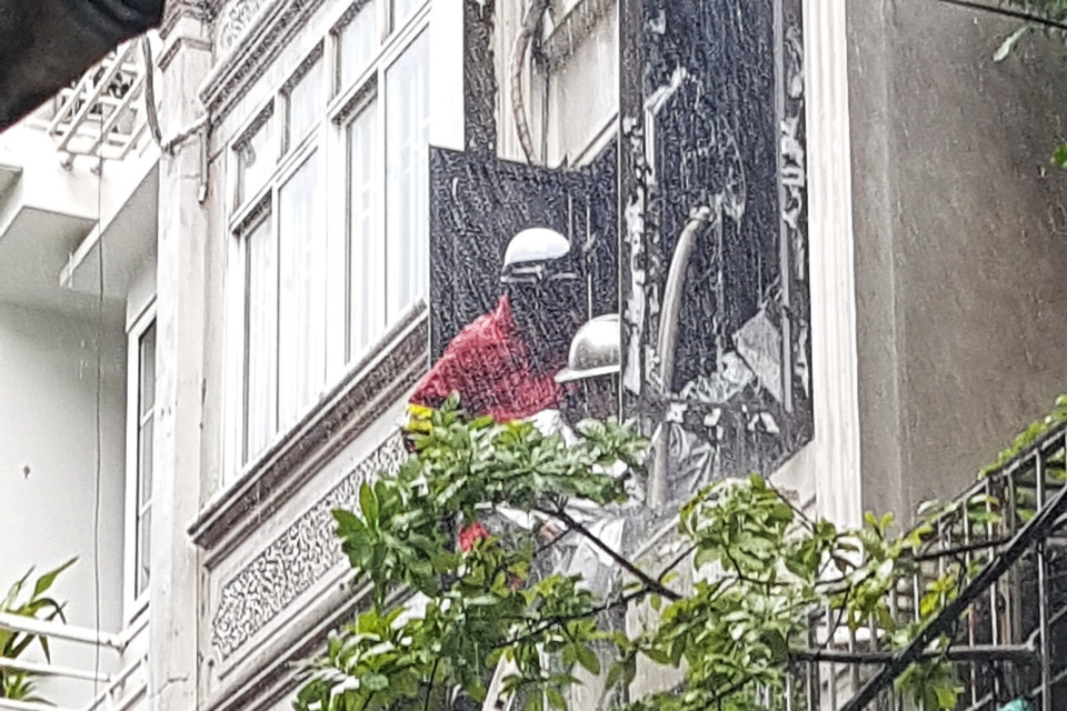 Lực lượng chức năng phải phá cửa để đưa vòi nước vào trong nhà dập lửa. (Ảnh: Tuấn Anh/TTXVN)