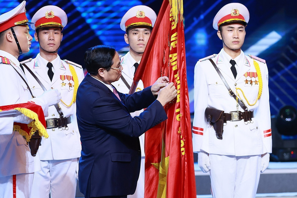 Thủ tướng Phạm Minh Chính gắn danh hiệu Anh hùng Lực lượng vũ trang nhân dân lên Cờ truyền thống của lực lượng phòng chống ma túy. (Ảnh: Dương Giang/TTXVN)