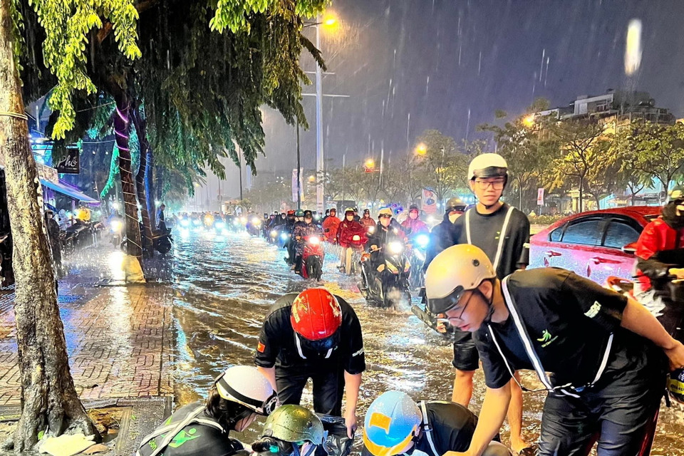 Đội Thanh niên tình nguyện Sài Gòn Xanh dọn rác kẹt trên miệng cống ở đường Kha Vạn Cân (thành phố Thủ Đức) để thoát nước. (Ảnh: Hồng Giang/TTXVN)