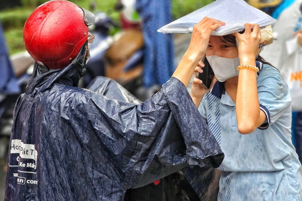 Mưa to vào thời điểm các thí sinh dự Kỳ thi tốt nghiệp THPT năm 2023 hoàn thành môn thi cuối khiến nhiều thí sinh, phụ huynh vất vả vượt mưa để về nhà. (Ảnh: Hồng Giang/TTXVN)