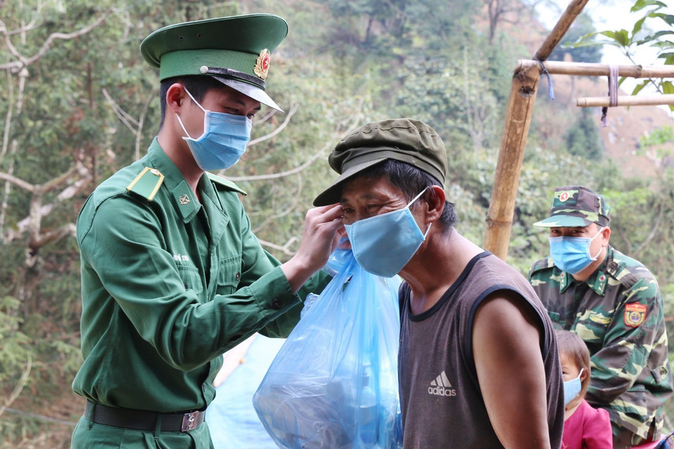 Cán bộ, chiến sỹ Đồn Biên phòng Pha Long, Bộ đội Biên phòng Lào Cai phát và hướng dẫn sử dụng khẩu trang phòng dịch cho người dân địa phương. (Ảnh: Dương Giang/TTXVN)