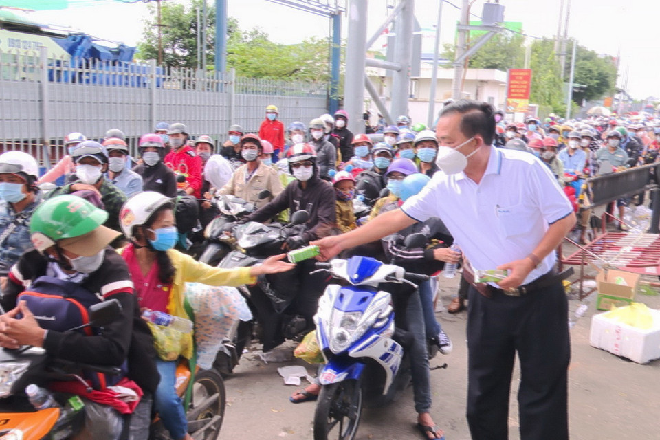 Lực lượng chức năng tỉnh An Giang hỗ trợ đồ ăn, nước uống, sữa cho người dân tại chốt kiểm soát dịch bệnh T2 của thành phố Long Xuyên gây ách tắc giao thông. (Ảnh: Công Mạo/TTXVN)