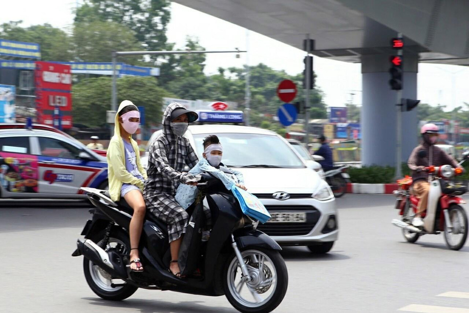 Trang phục bịt kín để chống chọi lại cái nắng gắt của người dân khi tham gia giao thông. (Ảnh: Danh Lam/TTXVN)