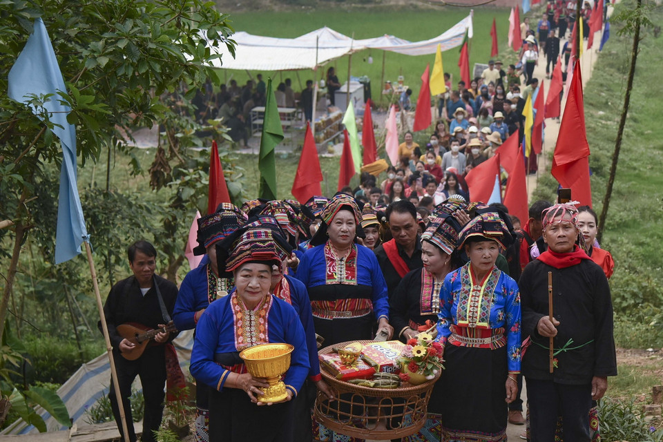  Đoàn người do bà mo dẫn đầu đi xin nước các gia đình trong bản với ý nghĩa cầu may. (Ảnh: Xuân Tư/TTXVN)