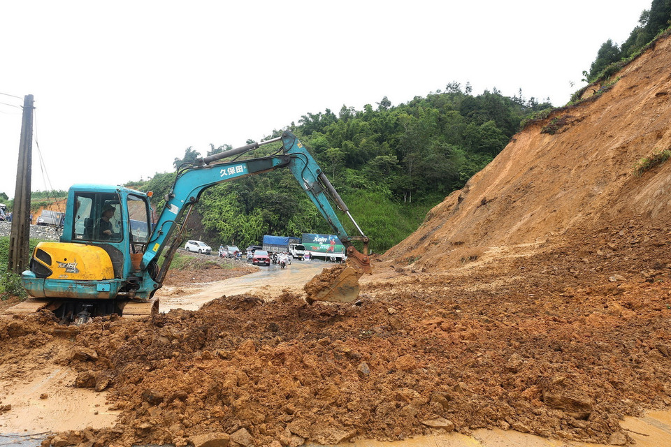 Máy xúc dọn lượng đất đá sạt ra đường để đảm bảo an toàn giao thông tại tỉnh Lào Cai. (Ảnh: Quốc Khánh/TTXVN)