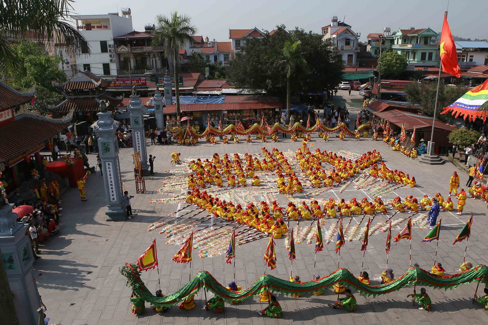  Các thanh niên nam nữ trong làng sẽ mặc áo cánh vàng, quần trắng, thắt lưng vải đỏ thắt múi đầu rìu, đầu buộc khăn lụa theo sự chỉ huy của các Tổng cờ sẽ lần lượt xếp thành chữ “Mẫu nghi thiên hạ.” (Ảnh: Công Luật/TTXVN)