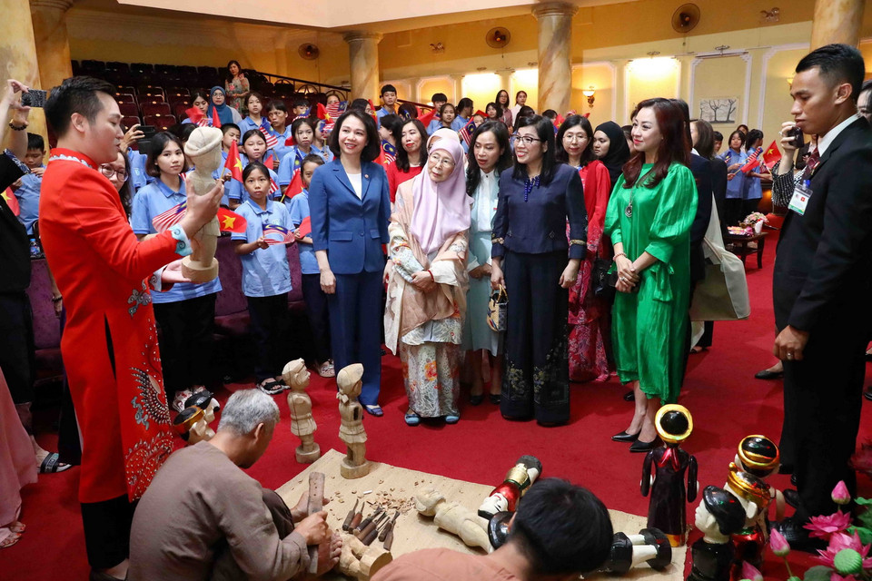 Phu nhân Thủ tướng Việt Nam Lê Thị Bích Trân và Phu nhân Thủ tướng Malaysia Dato' Seri Dr. Wan Azizah binti Dr. Wan Ismail nghe giới thiệu công việc tạo hình quân rối nước của các nghệ nhân. (Ảnh: Phạm Kiên/TTXVN)