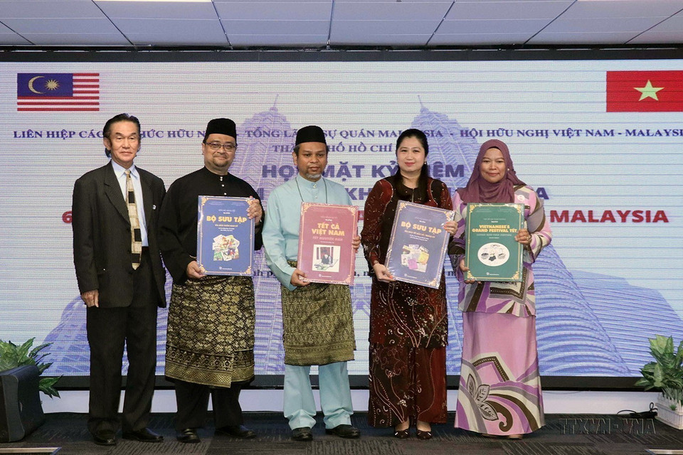 Tổng lãnh sự Wong Chia Chiann và các nhân viên Tổng lãnh sự quán Malaysia tại TP Hồ Chí Minh nhận sách giới thiệu về Tết truyền thống Việt Nam tại buổi họp mặt kỷ niệm lần thứ 65 ngày Quốc khánh Malaysia, ngày 9/9/2022. (Ảnh: Xuân Khu/TTXVN)